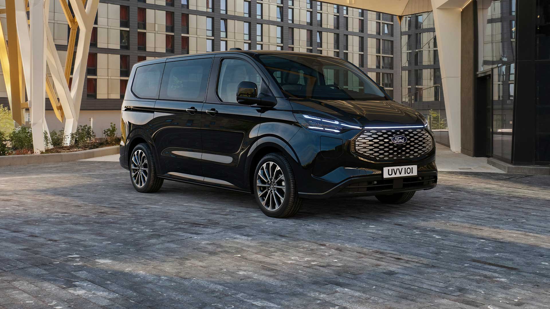 Schwarzer Ford E-Tourneo Custom vor modernem Gebaeude geparkt