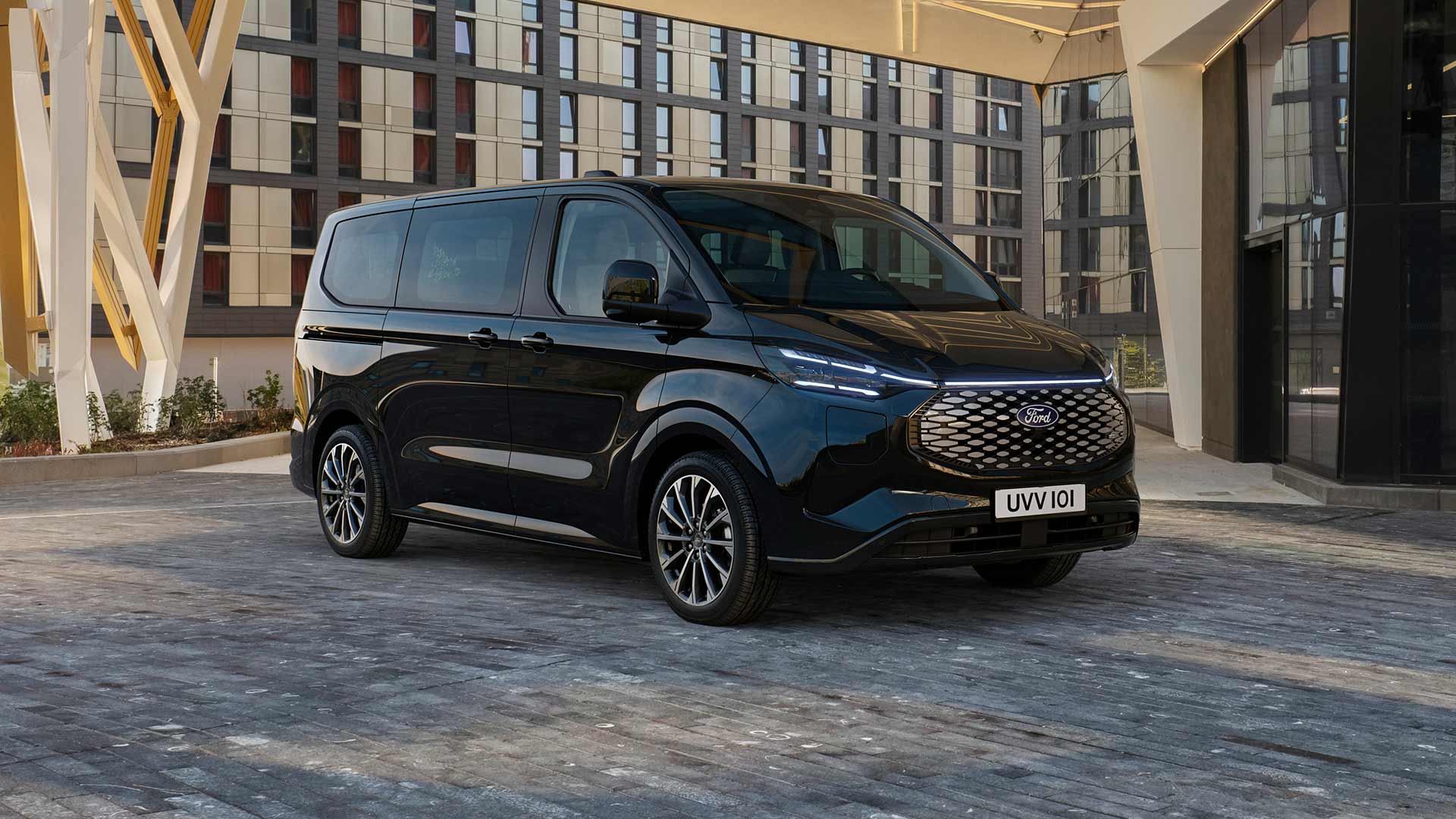 Schwarzer Ford E-Tourneo Custom vor modernem Gebaeude geparkt