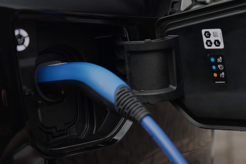 Nahaufnahme eines blauen Ladekabels im Ladeanschluss eines Elektrofahrzeugs