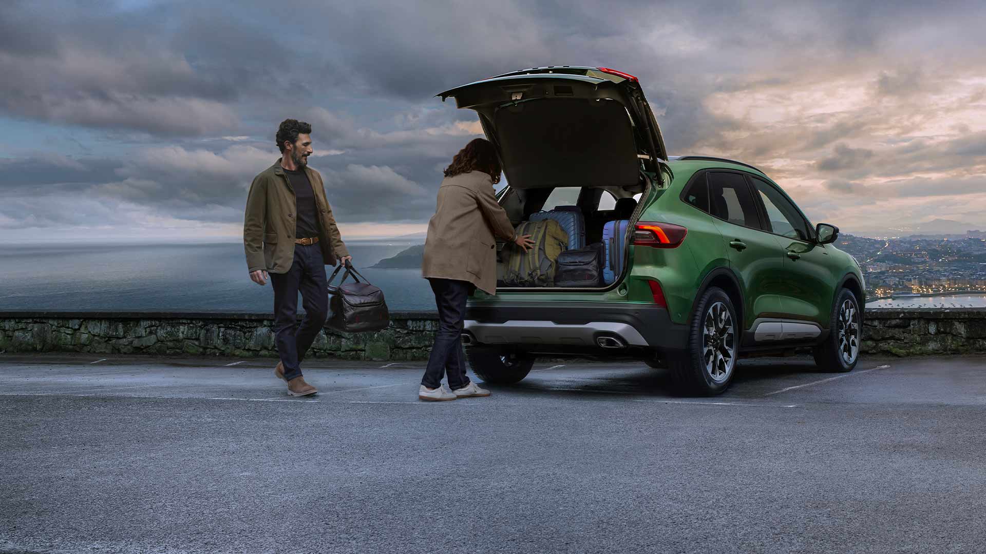 Zwei Personen laden mehrere Koffer in den geräumigen Kofferraum des Ford Kuga.