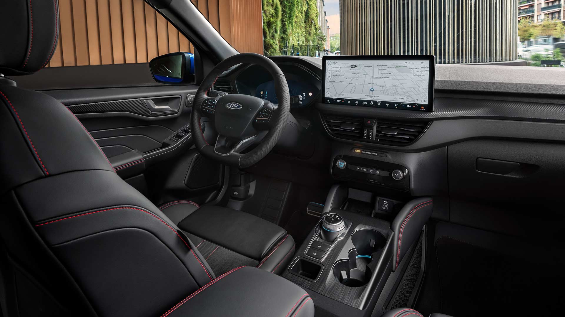 Ford Kuga Innenraum mit Ford-Logo-Lenkrad, großem SYNC® 4-Touchscreen und schwarzen Sitzen mit roten Nähten.
