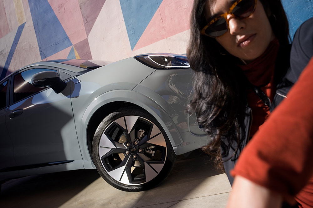 Primer plano de una persona junto a un Ford Puma® gris con un motor EcoBoost® de gasolina.