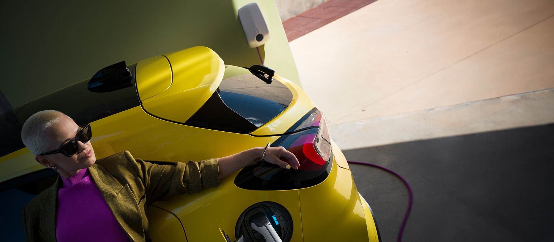 Nahaufnahme des Hecks eines gelben elektrischen Ford Puma Gen-E®, der an einen Home Charger angeschlossen ist.