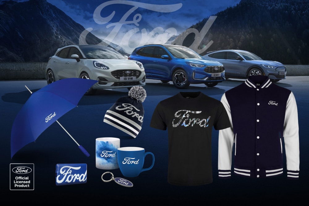 Ford Puma und Ford Kuga mit Ford Merchandise: Kleidung, Tassen, Regenschirm und Schlüsselanhänger, präsentiert vor einer Bergkulisse.