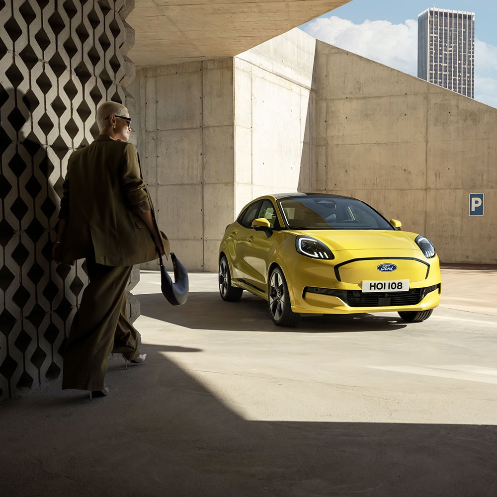 Eine Person geht auf den elektrischen Ford Puma Gen-E® in Gelb zu.