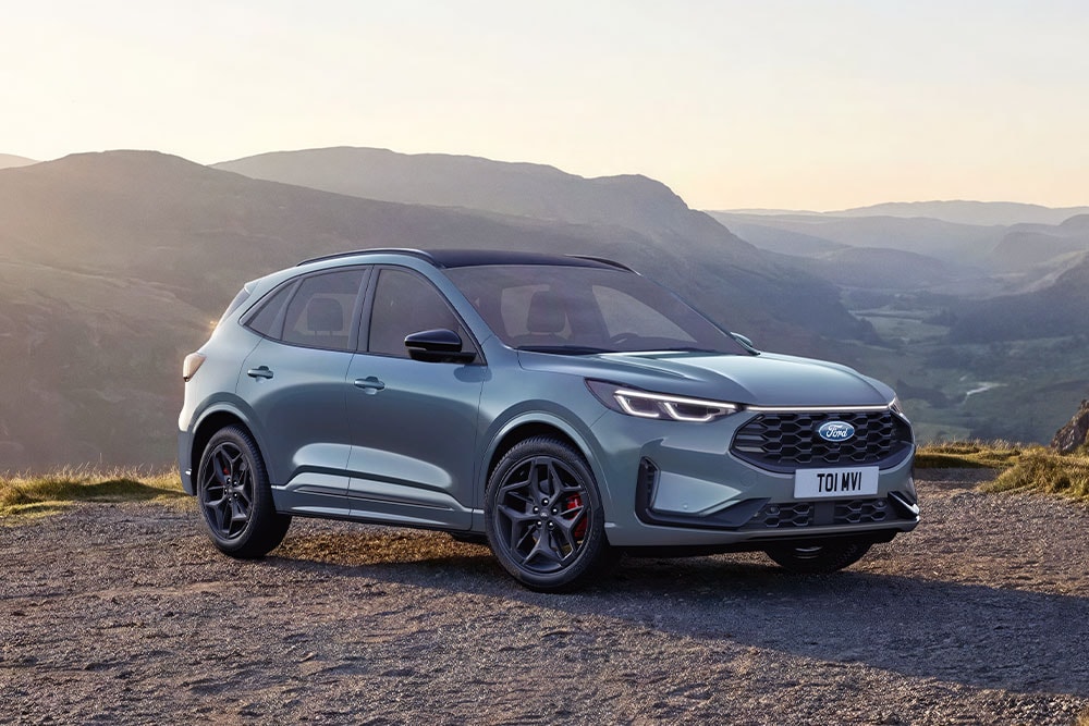 Ein grauer Ford Kuga parkt bei Sonnenuntergang auf einer Schotterstraße.