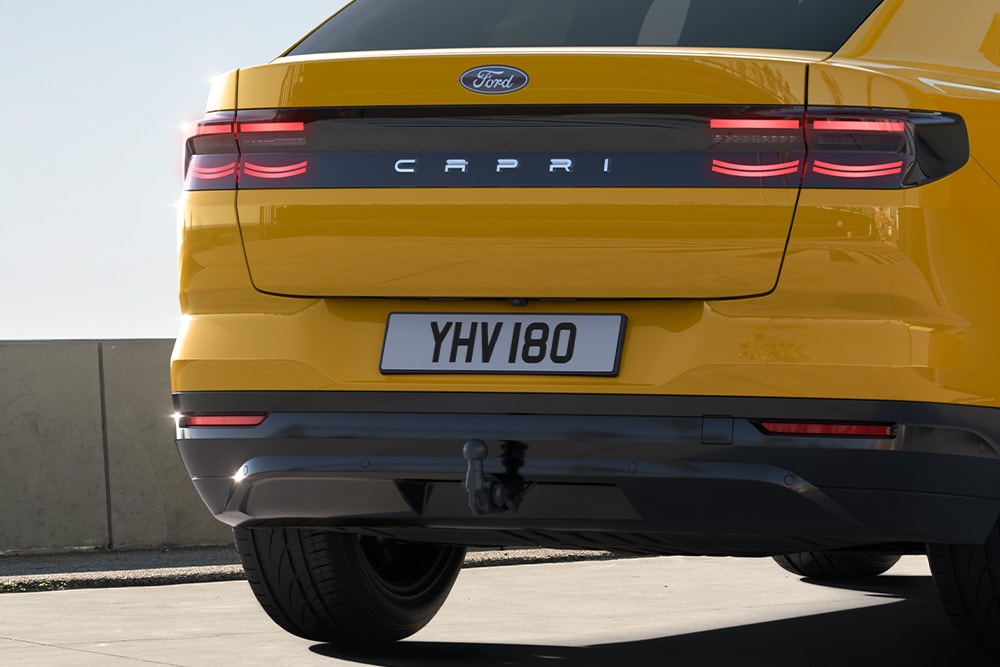 Rückansicht eines gelben Ford Capri®, der auf einer Stadtstraße fährt.