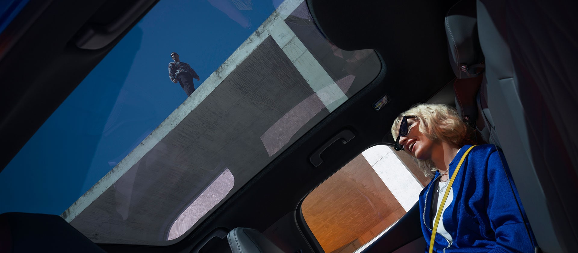 Eine Person sitzt in einem neuen Ford Capri® und genießt das Panoramadach.