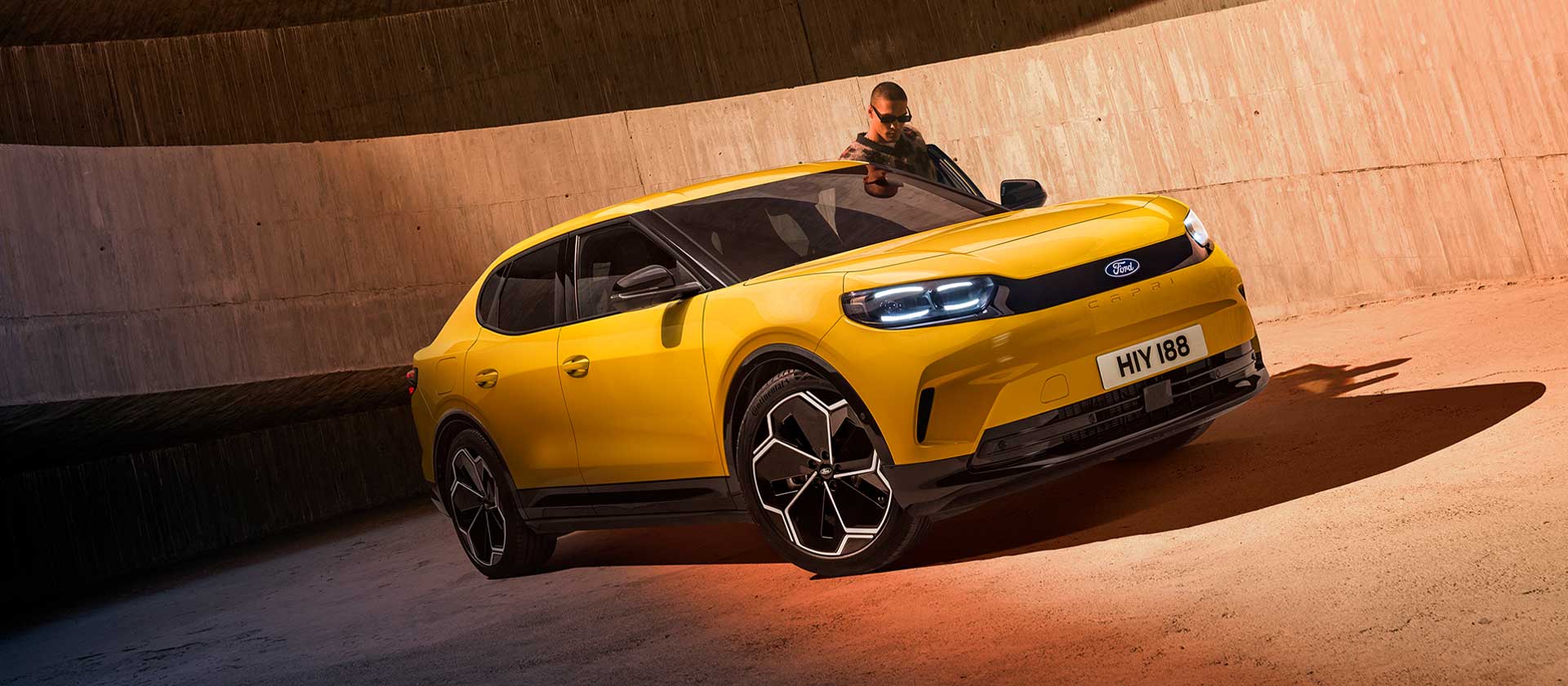Ein neuer gelber vollelektrischer Ford Capri® SUV parkt auf einem Parkplatz.