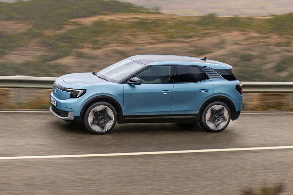 Seitenansicht eines hellblauen Ford Explorers, der auf einer Bergstraße fährt. Die 5-Sterne-Sicherheitsbewertung von Euro NCAP für 2024 wird in der unteren rechten Ecke angezeigt.