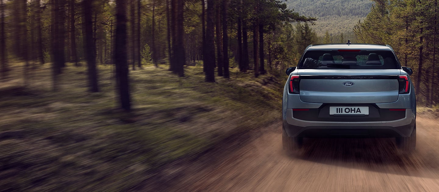 Rückansicht des Ford Explorer®, der auf einem Waldweg fährt und den EXPLORER-Schriftzug sowie das Ford-Emblem zeigt.