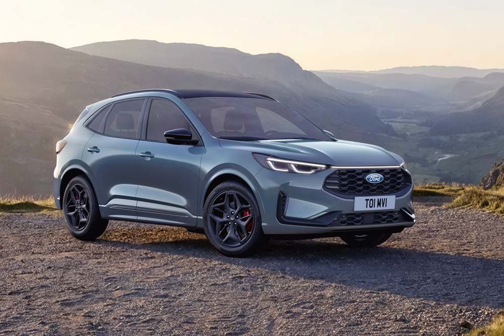 A blue Ford Kuga SUV parked outdoors with a mountainous background.