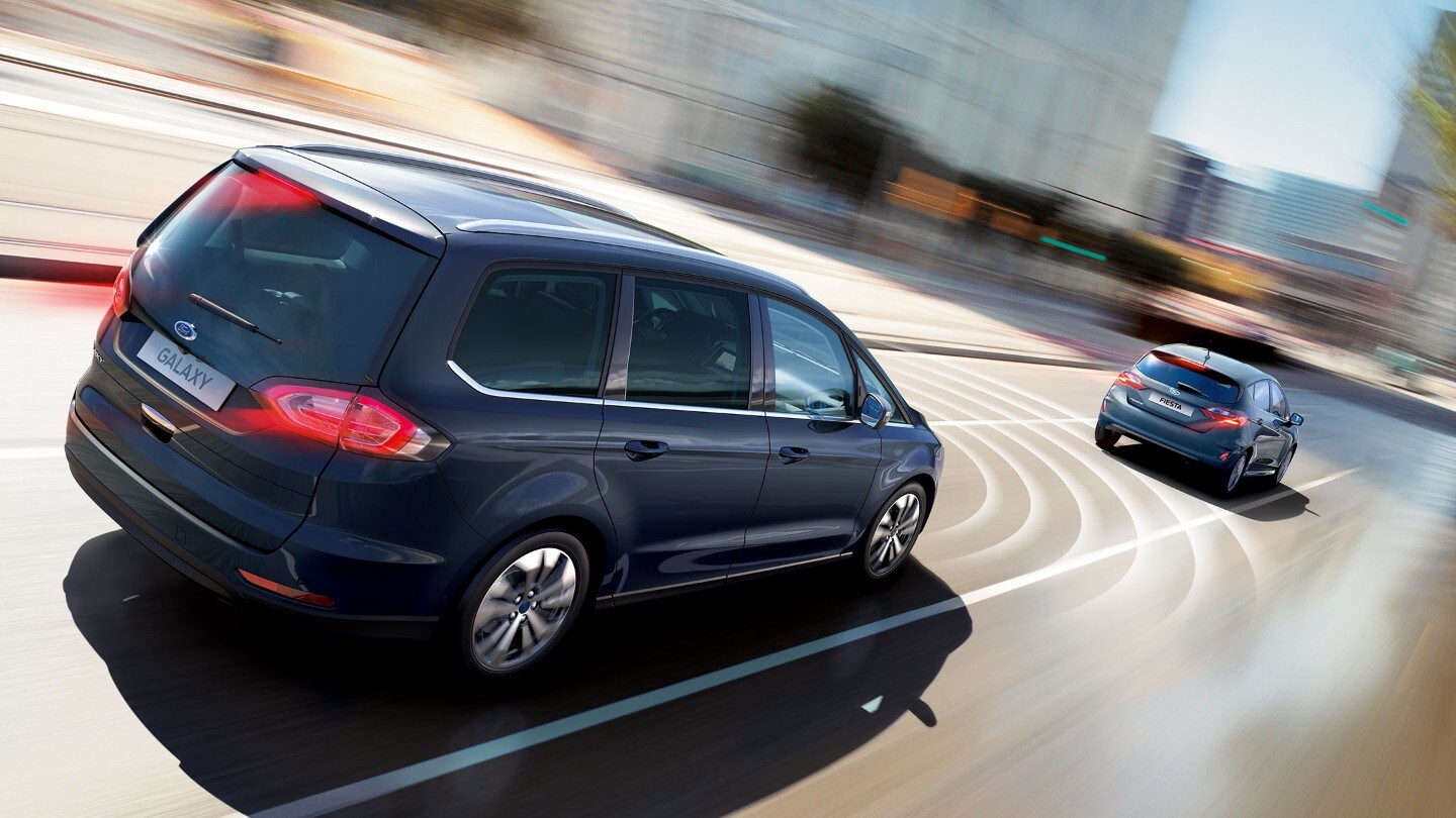 Ford Galaxy Hybrid in Blau. Dreiviertel von hinten. Fahrend auf einer Straße mit Visualisierung des Geschwindigkeitsbegrenzers
