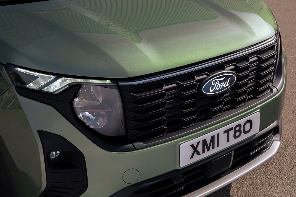Frontgrill und Scheinwerferdetails einer grünen Ford Tourneo Courier Großraumlimousine.