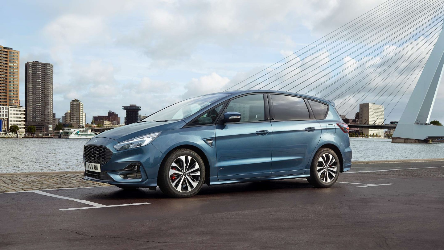Ford S-MAX Hybrid in Blau in der Seitenansicht parkt an einem Fluss vor einer Brücke