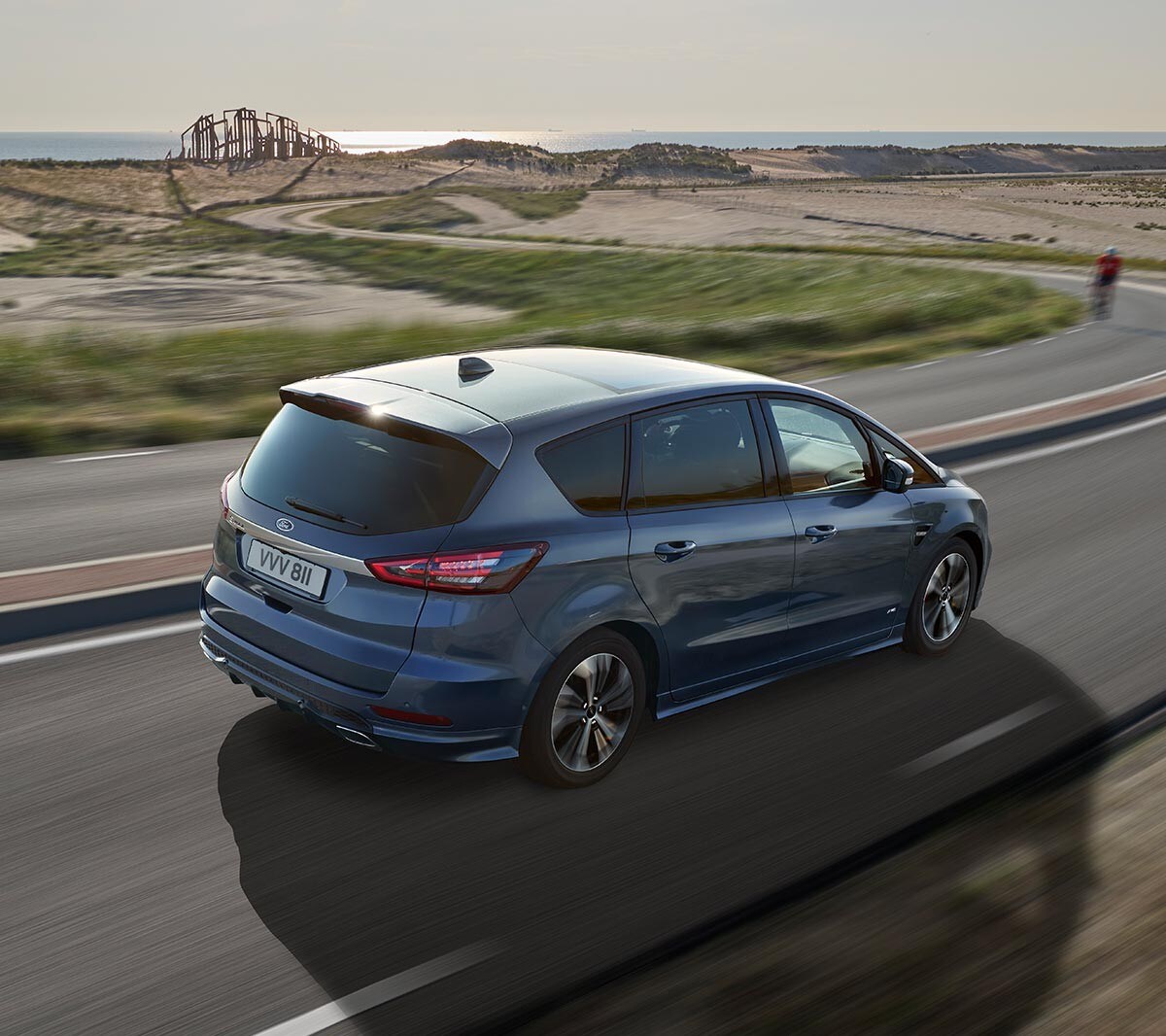 Ford S-MAX in Blau. ¾-Heckansicht. Fahrszene auf einer Küstenstraße