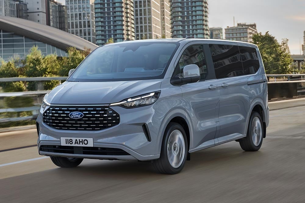 Silberner Ford Tourneo Custom faehrt auf einer Stadtstrasse