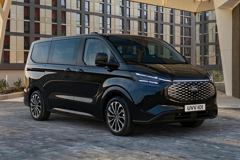 Schwarzer Ford E-Tourneo Custom vor modernem Gebaeude geparkt