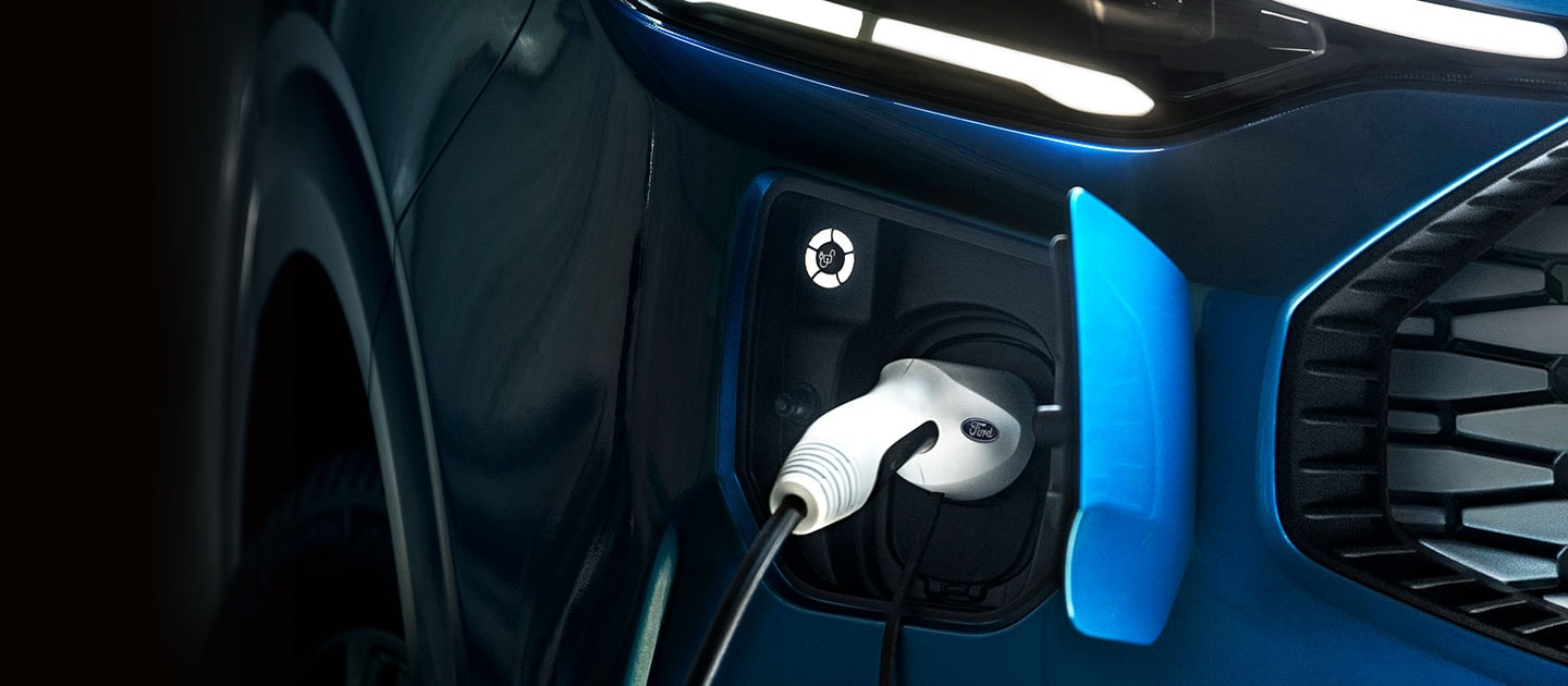 Nahaufnahme des Ladeanschlusses eines blauen Ford Tourneo Custom mit eingestecktem Ladekabel.