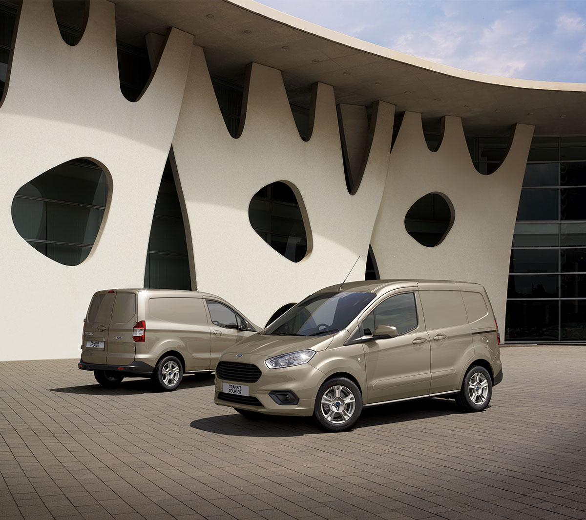 Ford Transit Courier in Champagner jeweils in  der ¾-Front und -Heckansicht parken voreinander