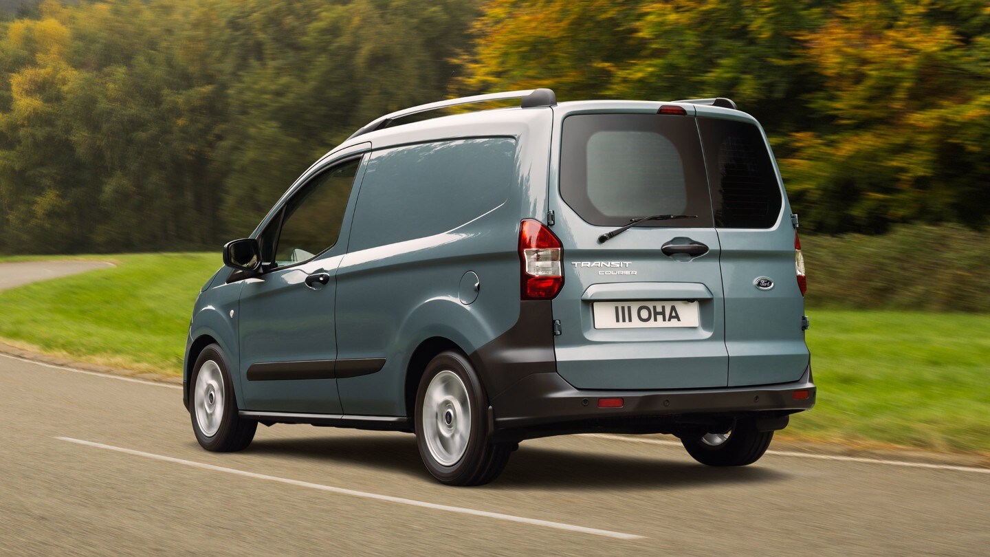 Ford Transit Courier in Grau ¾-Heckansicht fährt auf Landstraße