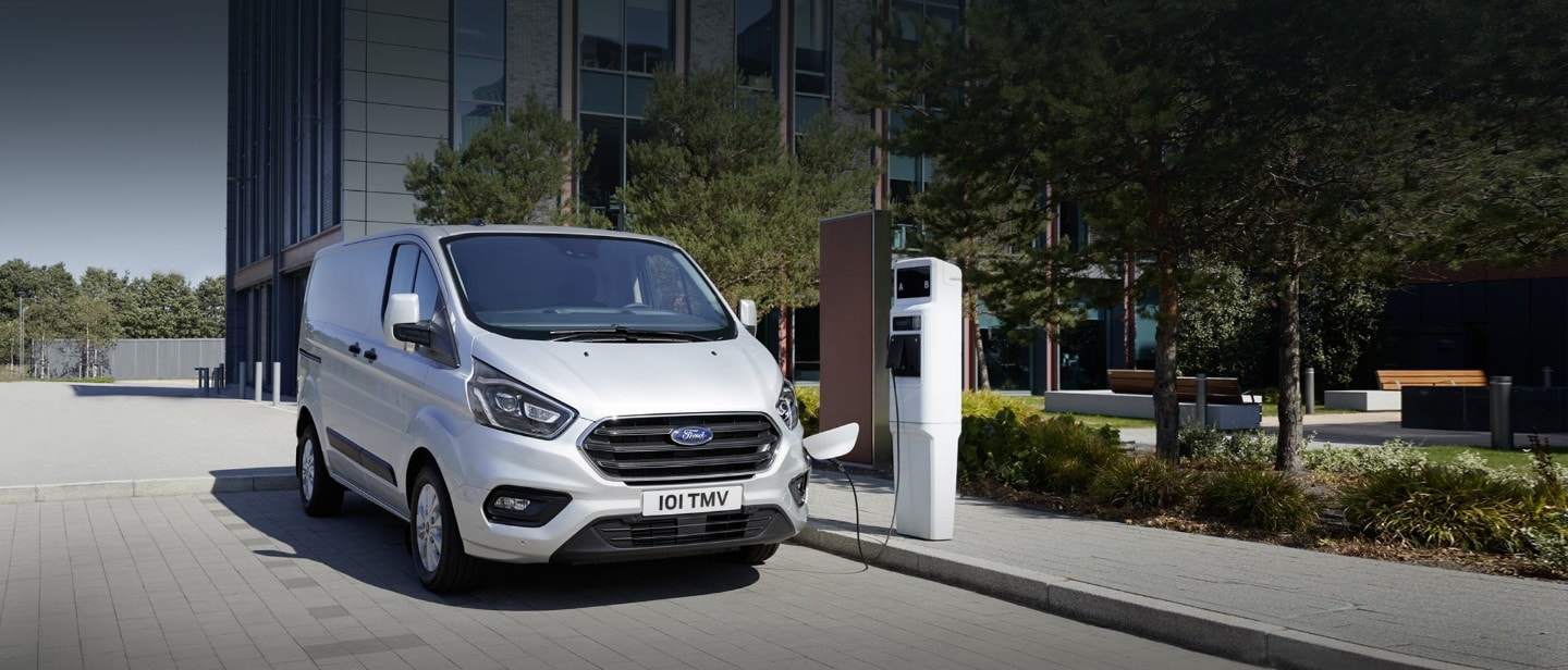 Ford Transit Custom PHEV driving in ciFord Transit Custom Kastenwagen LKW Plug-In Hybrid Silber ¾-Seitenansicht in Bewegung auf Straßety 