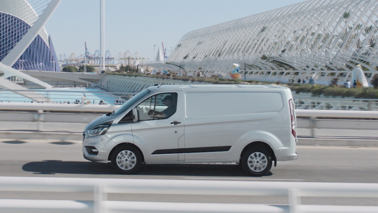 Ford Transit Custom Plug-in-Hybrid Seitenansicht weiß fährt über eine Brücke