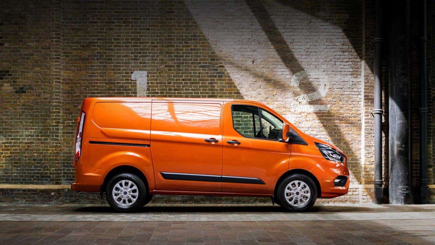 Ford Transit Custom Kastenwagen Orange Seitenansicht parkt neben Backsteingebäude