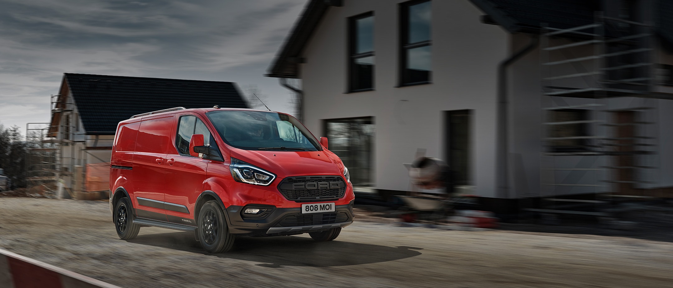 Transit Custom Trail on constructiFord Transit Custom Kastenwagen Trail Rot ¾-Frontansicht in Bewegung auf Baustellenstraßeon site