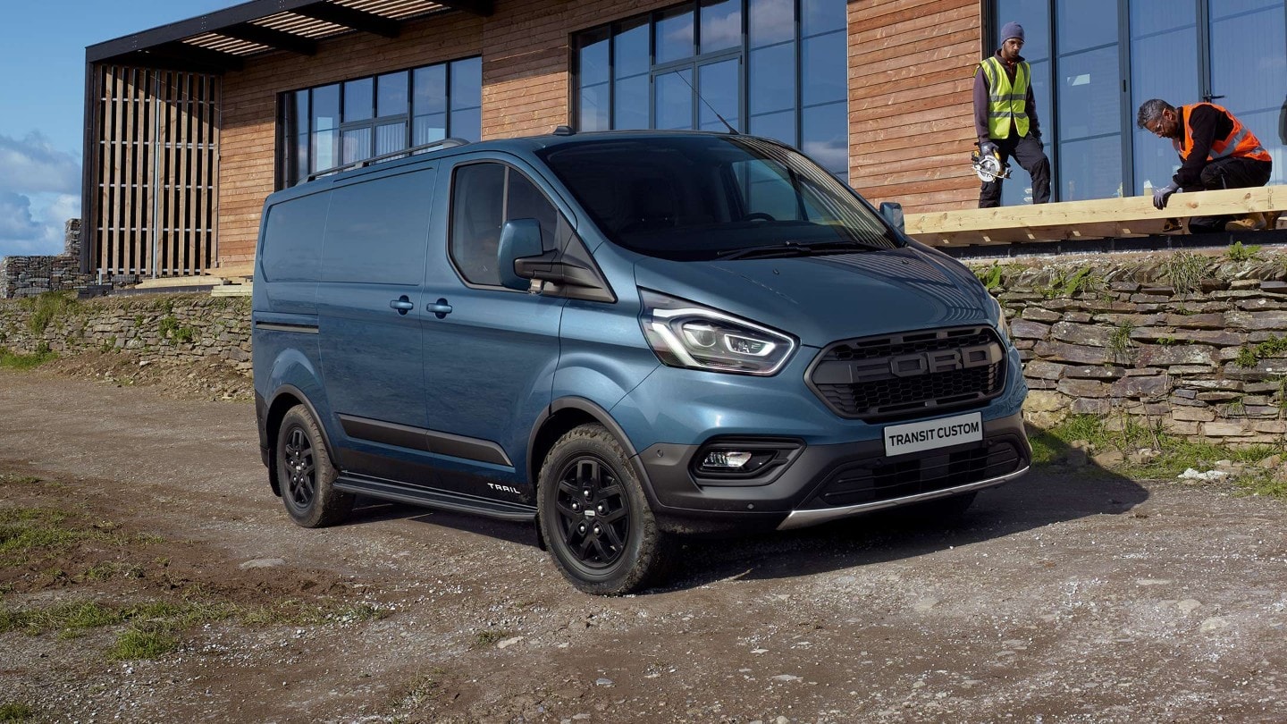 Ford Transit Custom Kastenwagen Trail Blau ¾-Seitenansicht parkt auf Baustellenstraße vor Gebäude