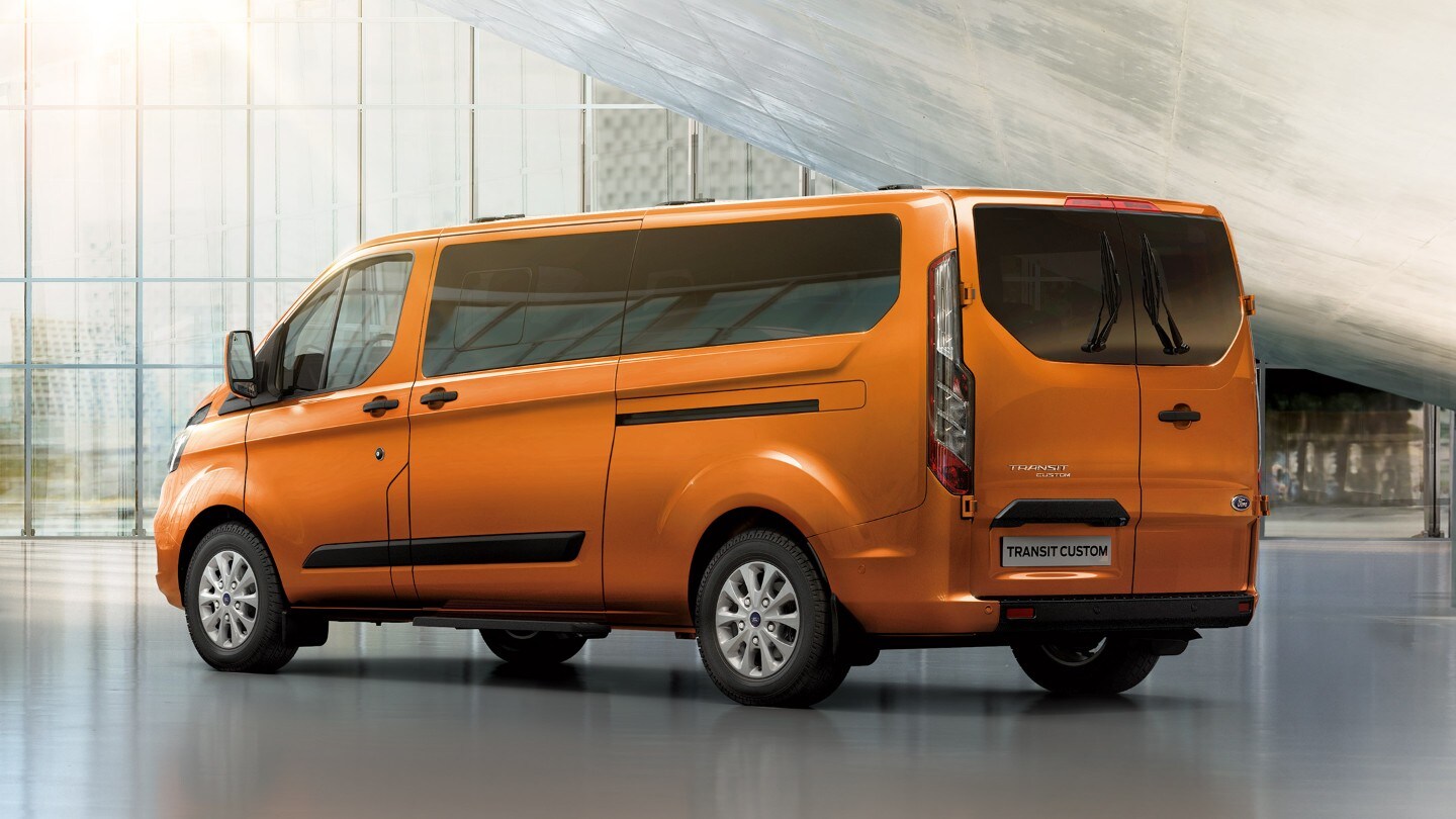Ford Transit Custom Kombi Orange ¾-Heckansicht parkt in Ausstellungshalle