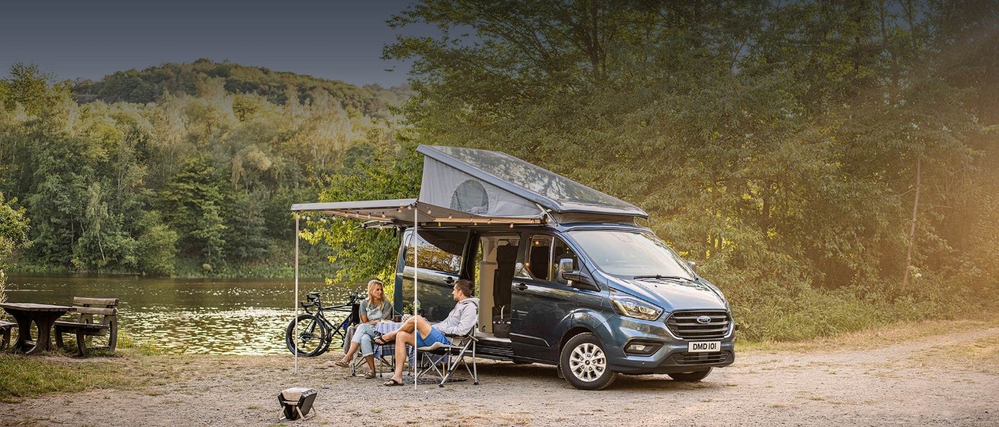 New Transit Custom Nugget Plus parked near lake with people sitting under canopy