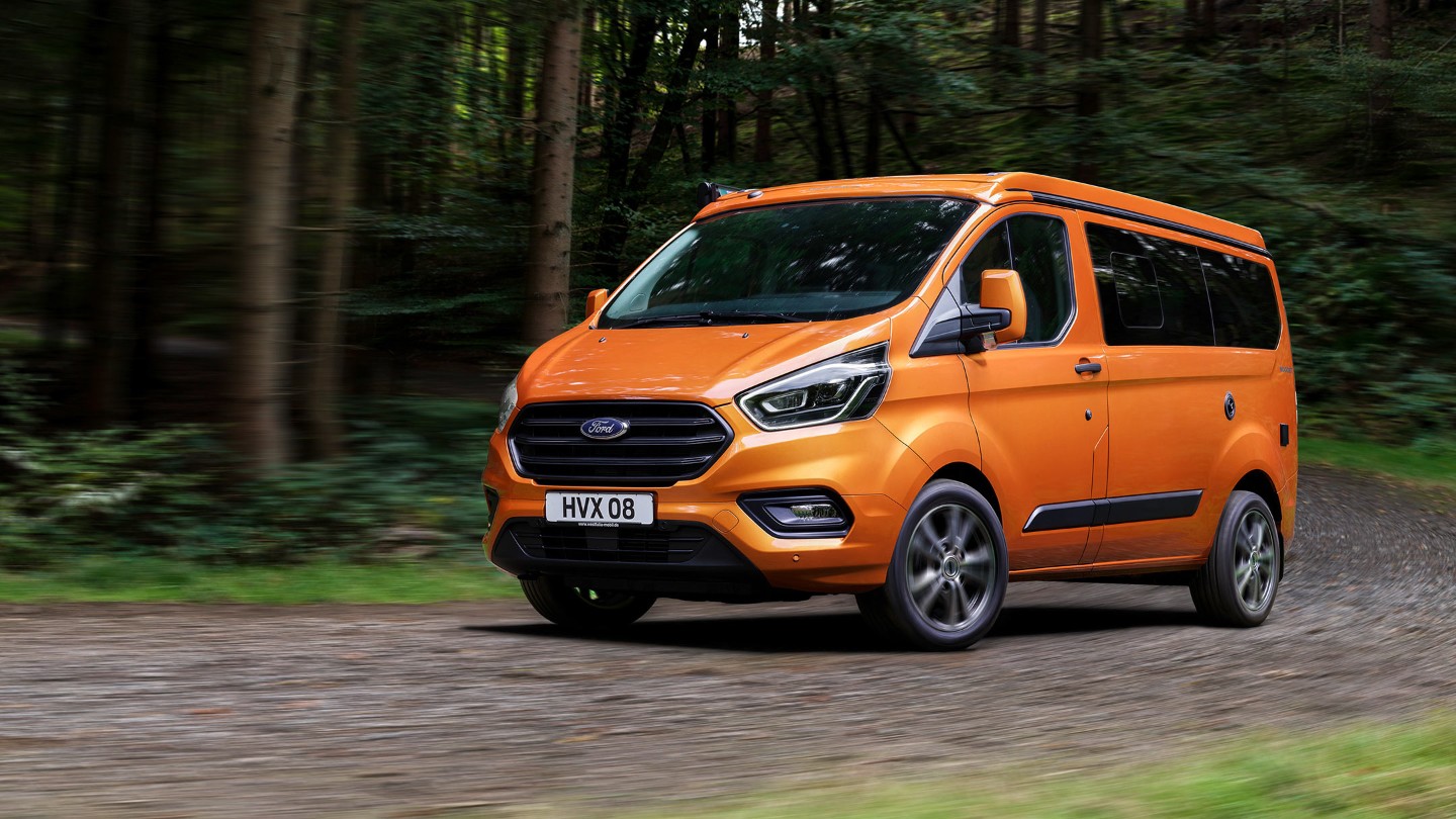 Ford Transit Custom Nugget Orange ¾-Frontansicht Aufstelldach parkt im Wald