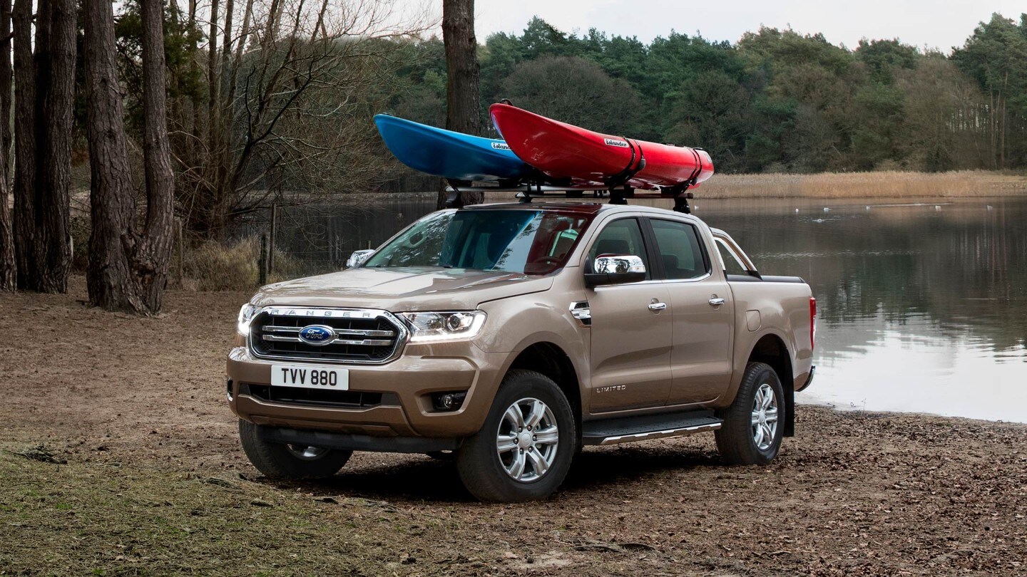 Ford Ranger Limited in Braun in der 3/4 Frontansicht beladen mit Kanus geparkt in der Nähe eines Sees