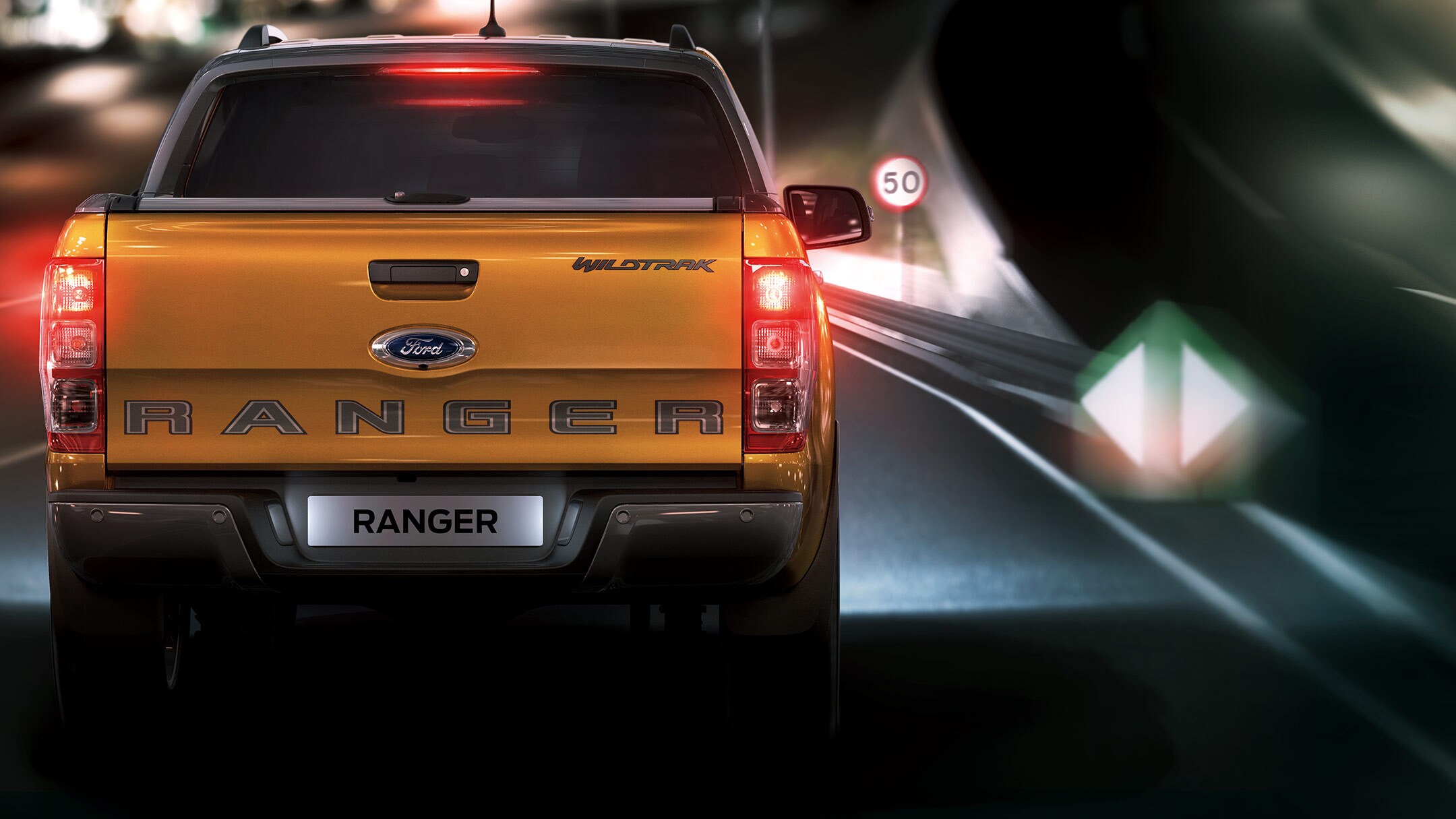 Ford Ranger Orange Heckansicht bei Nacht in Bewegung auf Straße 