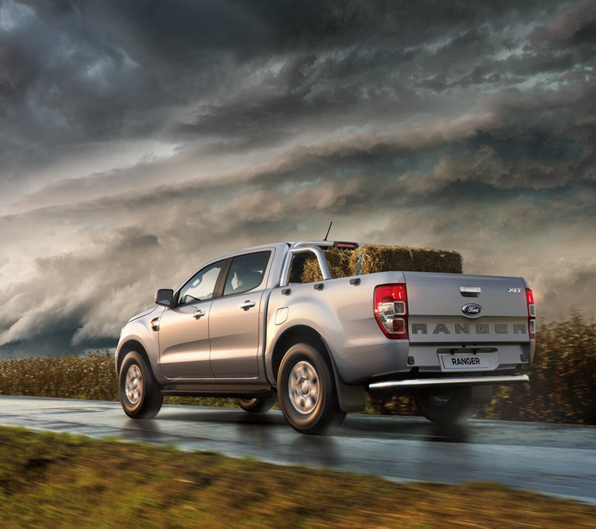 Ford Ranger XLT in Silber in der ¾ Heckansicht auf einer Landstraße umgeben von Maisfeldern