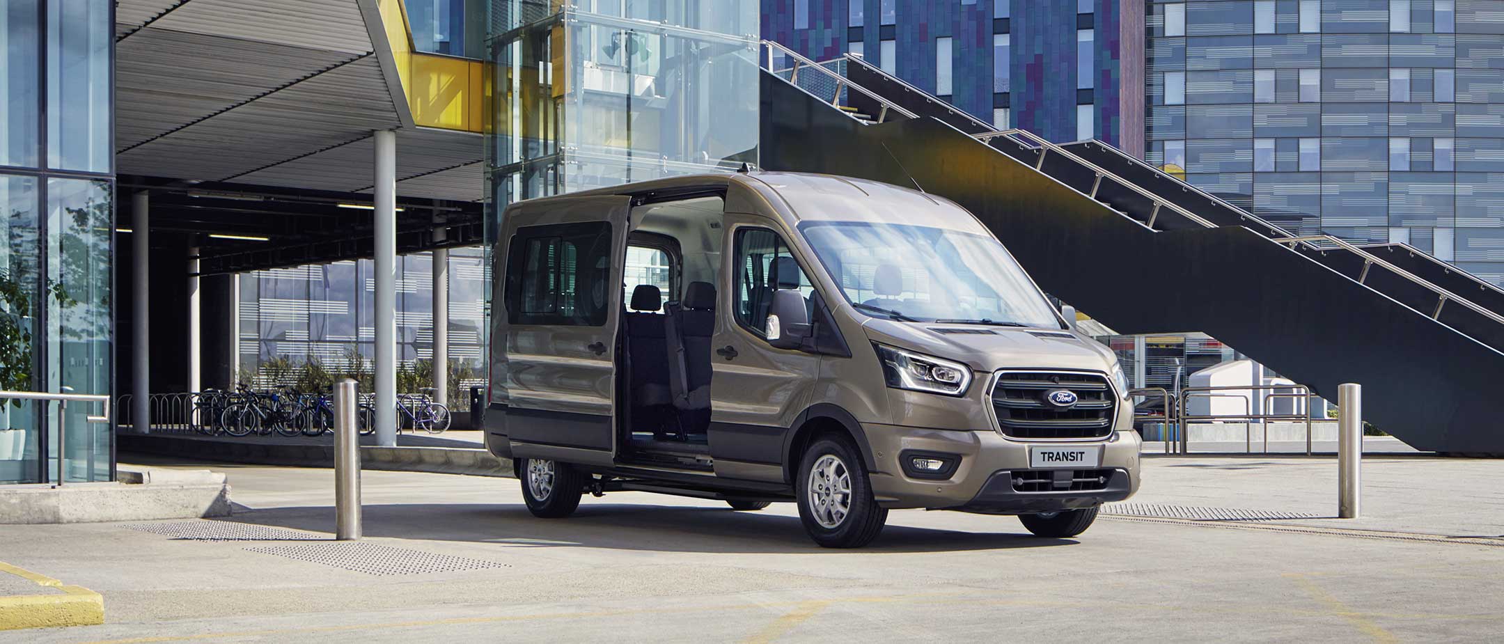 Ford Transit Minibus standing with side door open in front of modern building