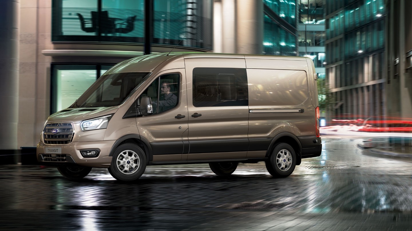 Ford Transit Doppelkabine LKW Champagner Seitenansicht parkt in Innenstadt vor Gebäude bei Nacht