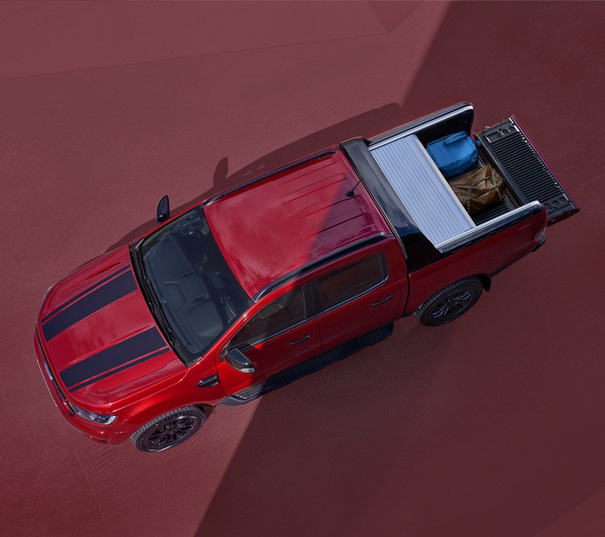 Ford Ranger Stormtrak rot Vogelperspektive mit geöffnetem Laderaumrollo parkt auf rotem Untergrund 