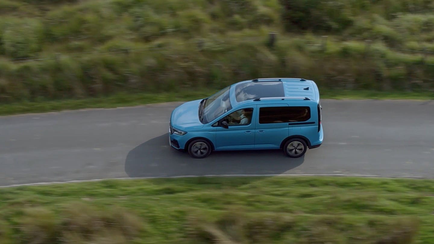 Ford Tourneo Connect in Hellblau Seitenansicht in der Vogelperspektive fährt auf Landstraße