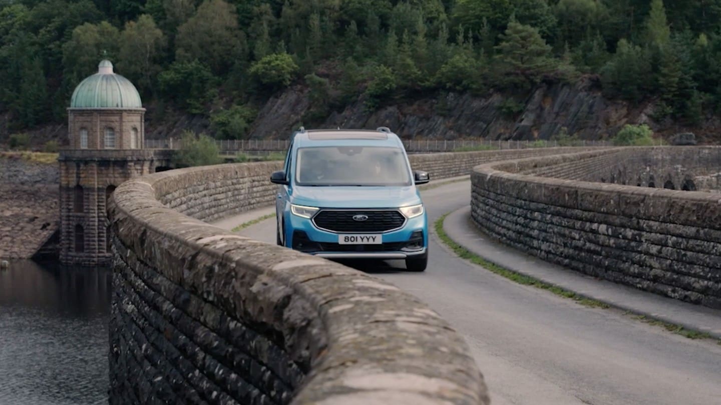 Ford Tourneo Connect in Hellblau Frontansicht fährt über kurvige Steinbrücke