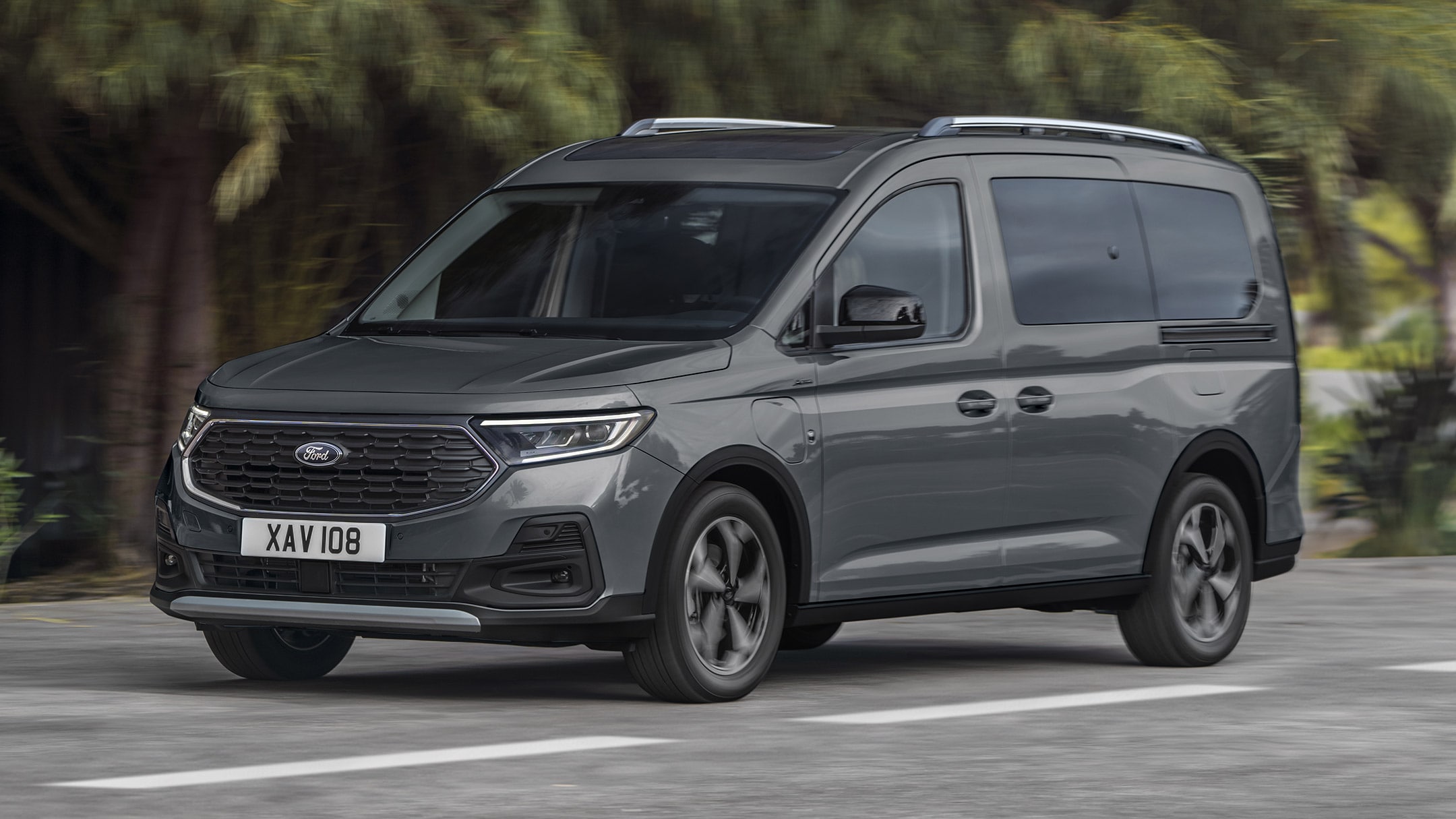 Ford Tourneo Connect in Grau ¾-Frontansicht fährt auf gebirgiger Landstraße mit Fluss im Hintergrund