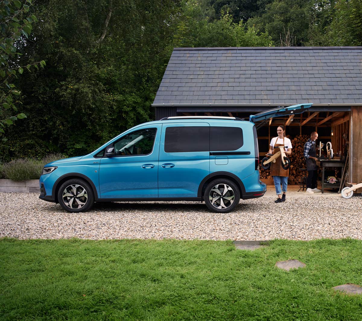 Ford Tourneo Connect in Hellblau Seitenansicht mit geöffneter Hecktür,  Frau belädt Gepäckraum