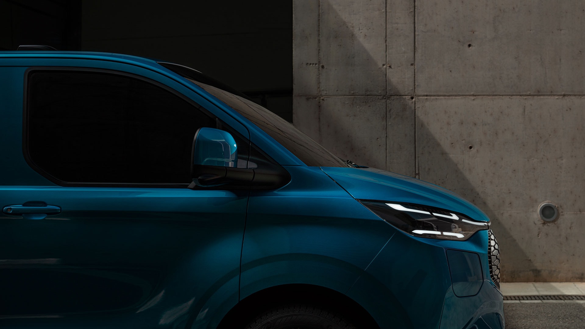 Nahaufnahme des LED-Scheinwerfers eines blauen Ford E-Transit Custom. 