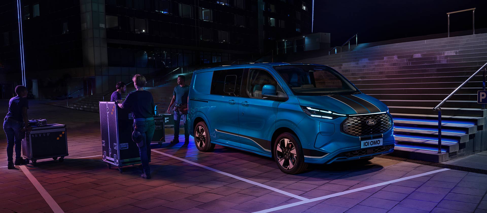 Blauer Ford E-Transit Custom Elektro-Transporter wird nachts beladen.  