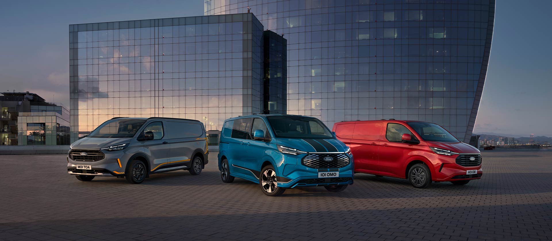 Drei Ford Transit Custom Sport Vans in Grau, Blau und Rot nebeneinander geparkt