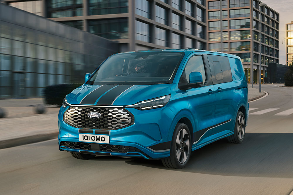 Blauer Ford E-Transit Custom Sport Doppelkabine fährt durch die Stadt. 