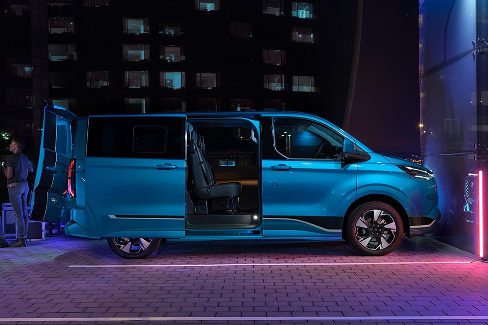 Blauer Ford E-Transit Custom Doppelkabine Elektro-Transporter mit offenen Tueren.  