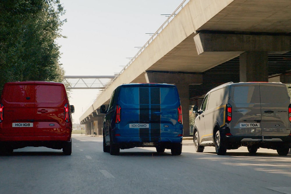Drei Ford Transit Custom Transporter fahren auf der Autobahn.  