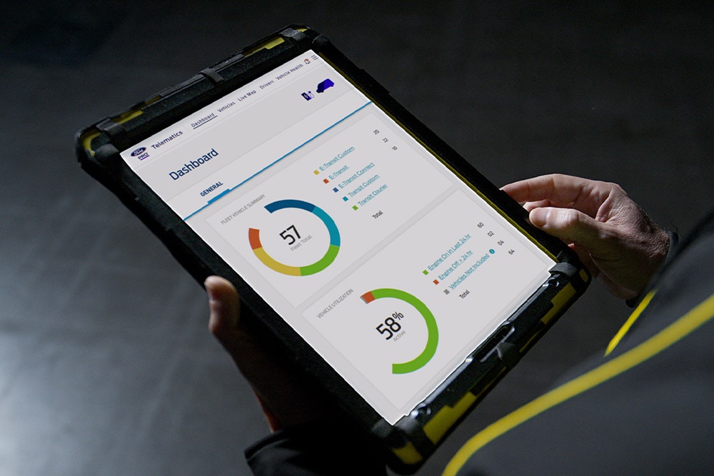 Person haelt Tablet mit Ford Pro Fahrzeugdaten.  